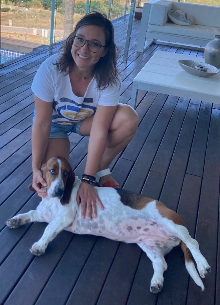 Miriam en terraza acariciando perro blanco con manchas marrones